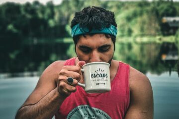 woman in pink tank top holding white ceramic mug